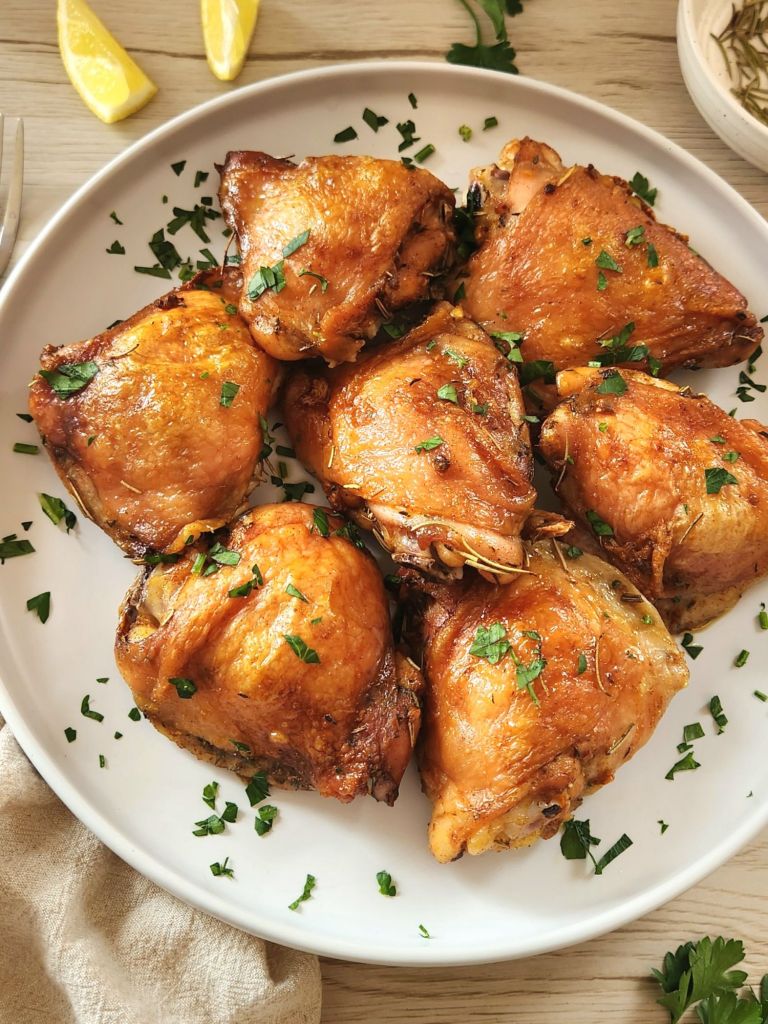 Juicy herb chicken thighs baked until golden brown in a white ceramic plate