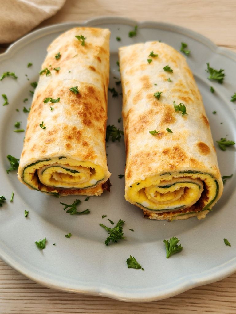 Close-up of a high-protein tortilla omelette wrap served on a sage green plate