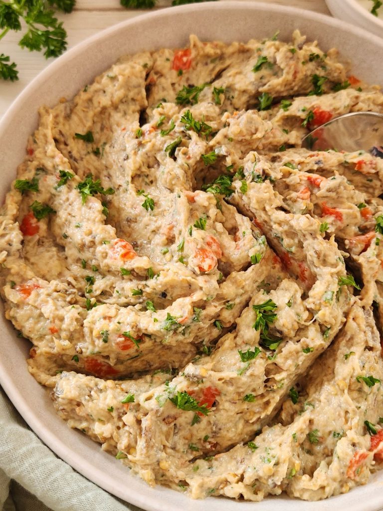 Creamy Eggplant Tahini Salad with roasted bell pepper, walnuts and parsley served in a beige bowl.