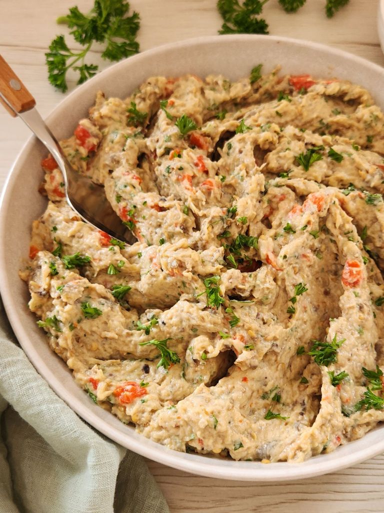 Creamy Eggplant Tahini Salad with roasted bell pepper, walnuts and parsley served in a beige bowl.