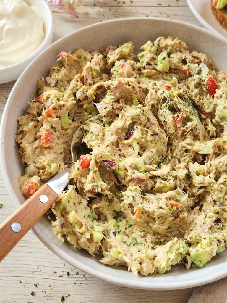 Creamy tuna salad with yogurt, avocado, bell pepper in a beige bowl 