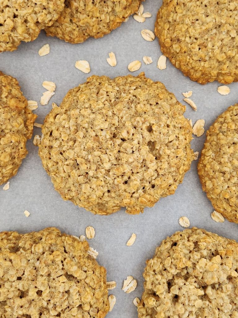 Healthy oatmeal cookies cooling on 
parchment paper, golden brown with crisp edges and a soft center.