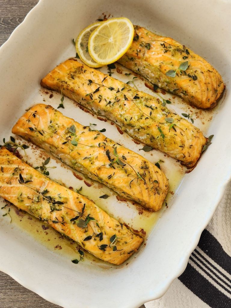 Fillets of baked salmon with basil, thyme and slices of lemon in baking dish