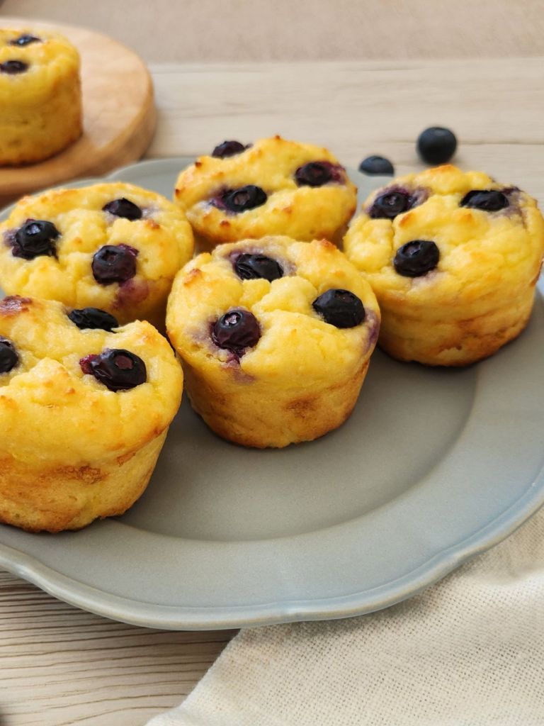 Close-up of high-protein cottage cheese pancake cups with fresh blueberries served on a sage green plate