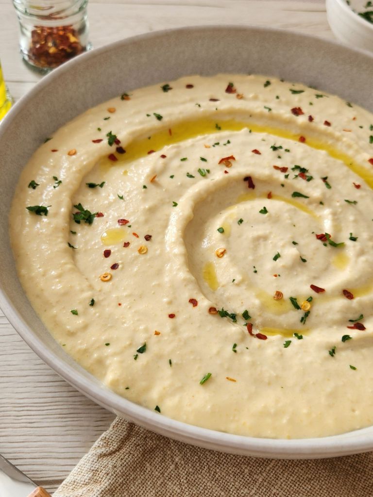 Smooth and creamy hummus close-up showing texture and garnish of olive oil and paprika
