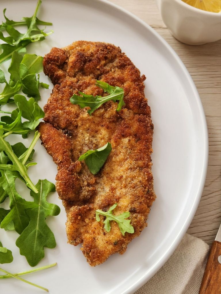Close up of a Crispy golden chicken schnitzel served on a white plate