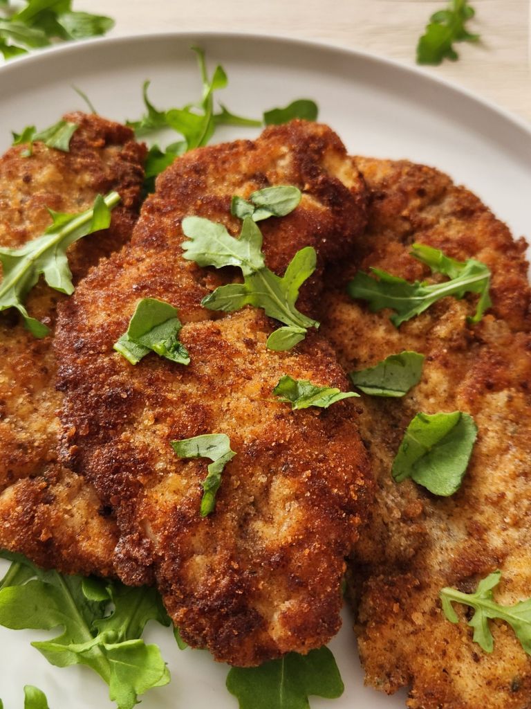 Close-up of Crispy golden chicken schnitzel served on white plate