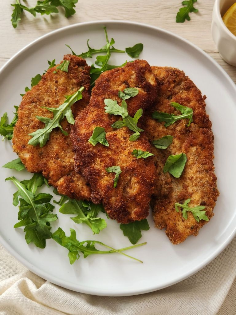 Crispy golden chicken schnitzels served on white plate