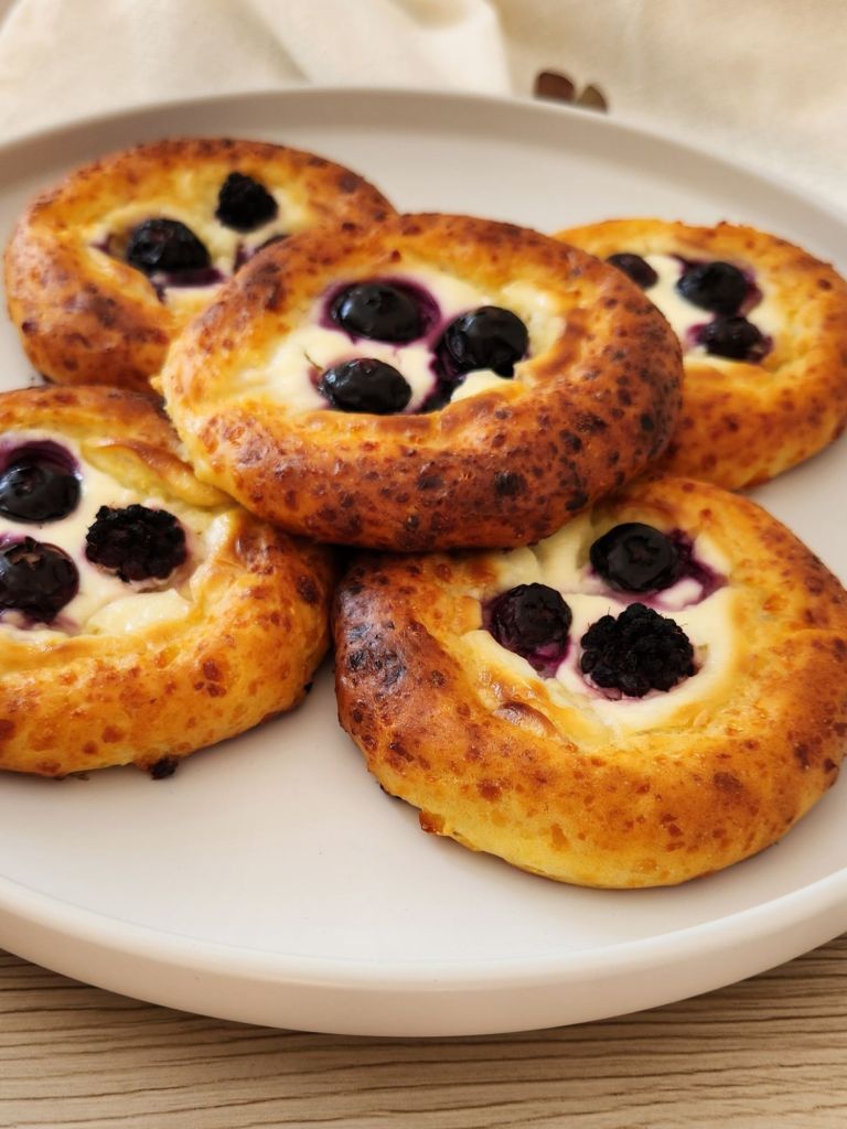 Close up of golden High-Protein Cottage Cheese Brioche Buns stacked on a white plate