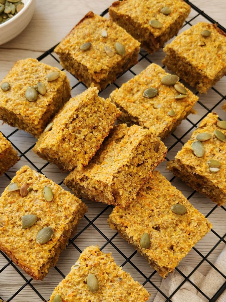 Healthy carrot cake banana oat bars topped with pumpkin seeds on a cooling rack