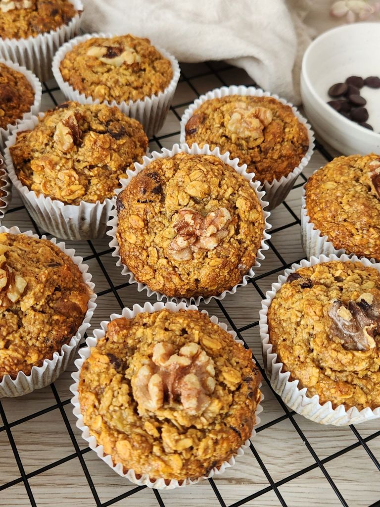 Close up of golden oat banana muffins with walnuts on top cooling on a rack