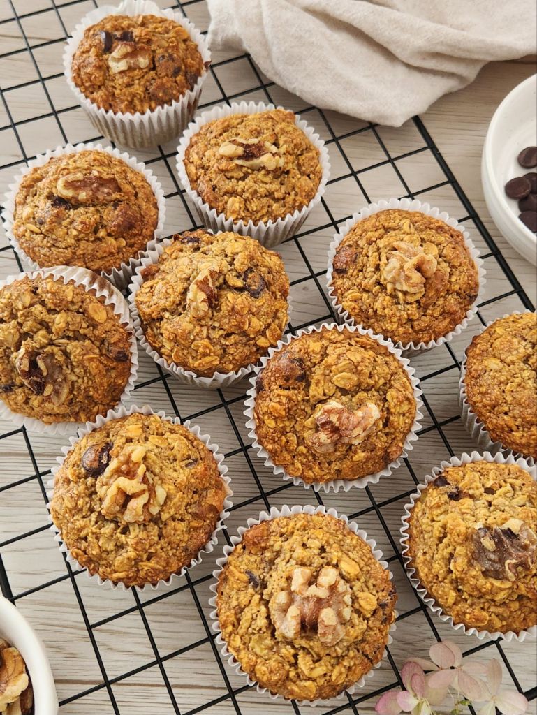 Golden oat banana muffins with walnuts on top cooling on a rack
