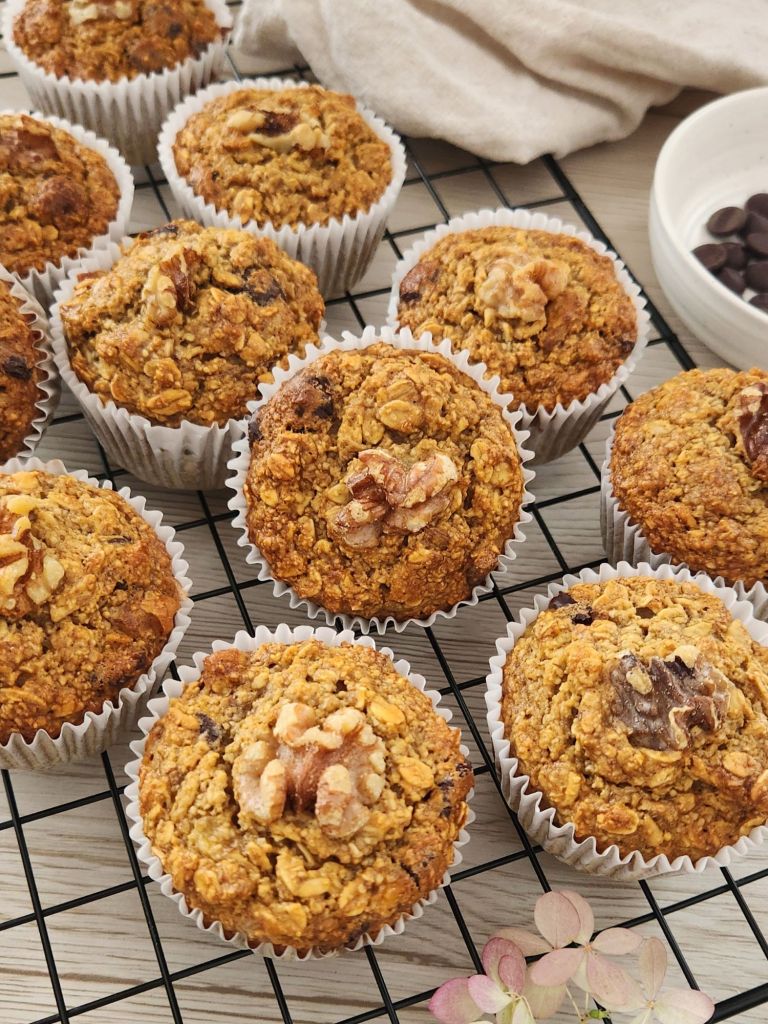 Golden oat banana muffins with walnuts on top cooling on a rack