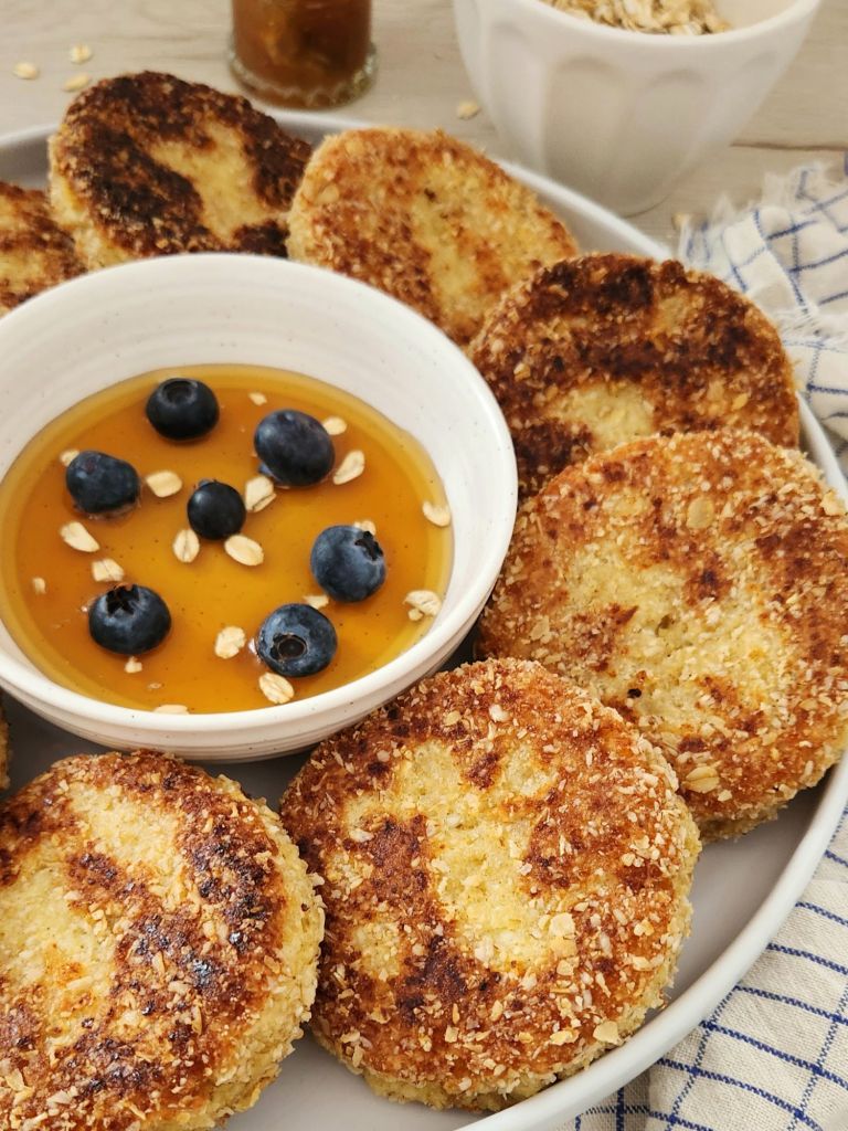 Fluffy cottage cheese oat pancakes coated in oat flour, served with maple syrup and blueberries.