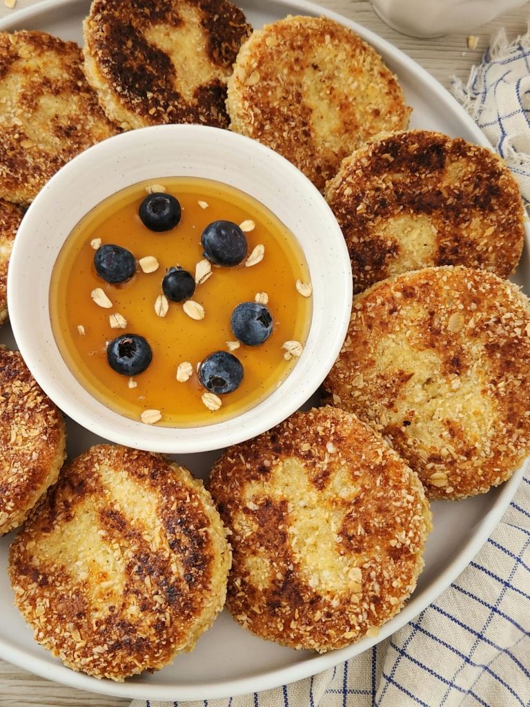 Fluffy cottage cheese oat pancakes coated in oat flour, served with maple syrup and blueberries.