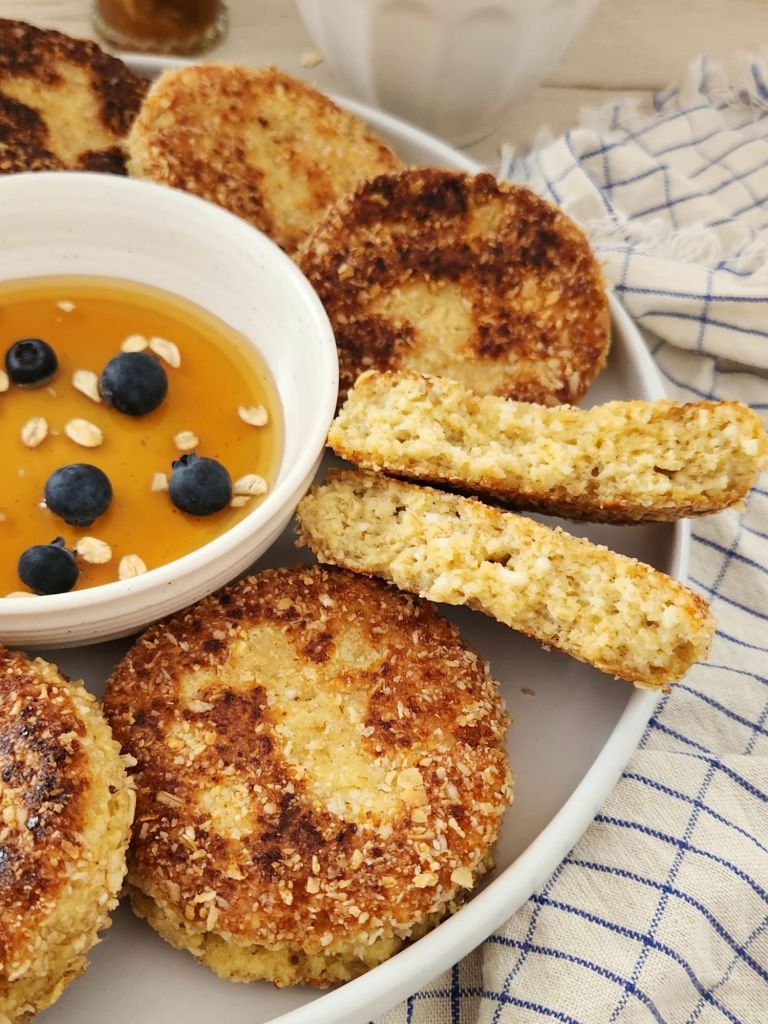 Close-up to see texture of Fluffy cottage cheese oat pancakes coated in oat flour, served with maple syrup and blueberries.