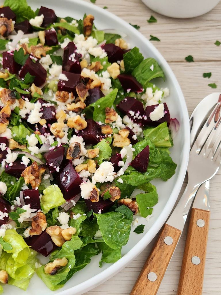 Close-up of Beet, Feta & Romaine Salad with Toasted Walnuts served on a white plate