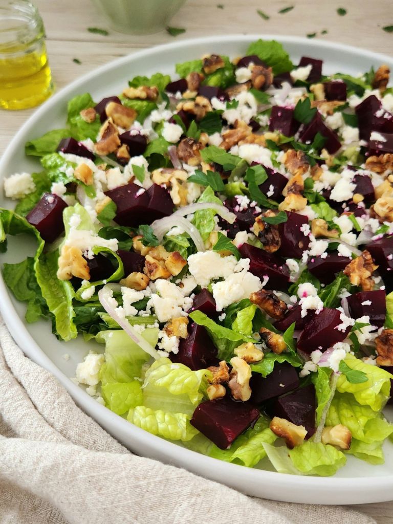 Close-up of Beet, Feta & Romaine Salad with Toasted Walnuts served on a white plate