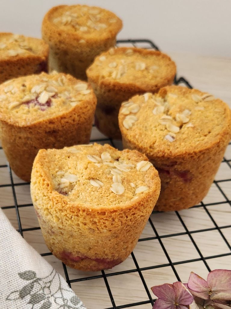 Gluten-free raspberry almond muffins on a cooling rack topped with rolled oats