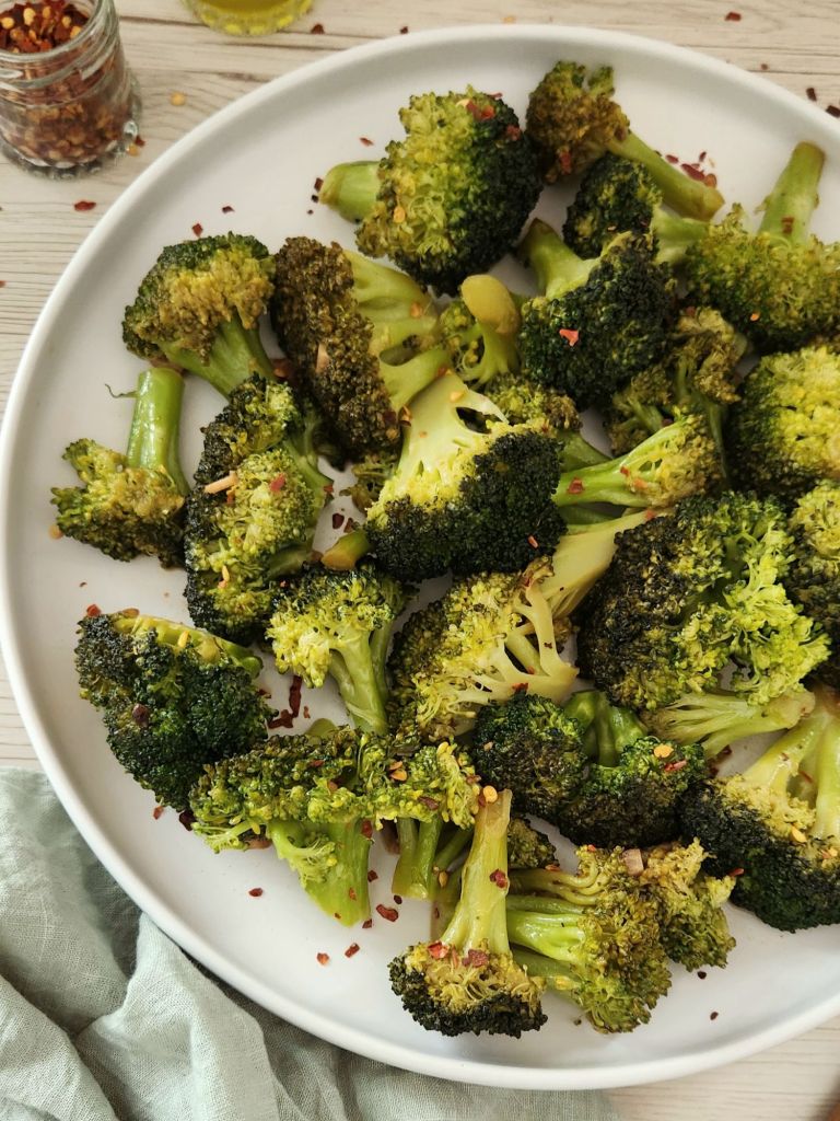 Chopped green broccoli sautéed with fresh garlic and soy sauce, served on a white plate