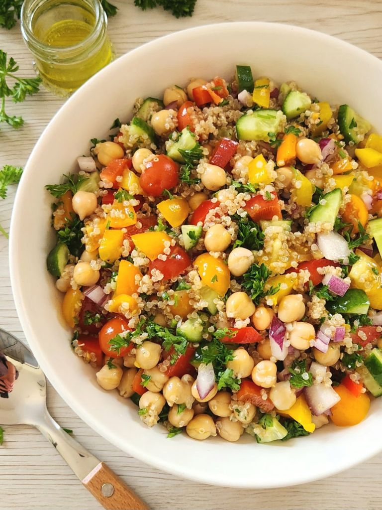 Healthy quinoa chickpea salad with fresh vegetables and lemon herb dressing in a white bowl