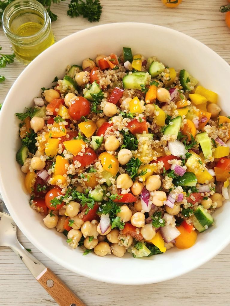 Healthy quinoa chickpea salad with fresh vegetables and lemon herb dressing in a white bowl