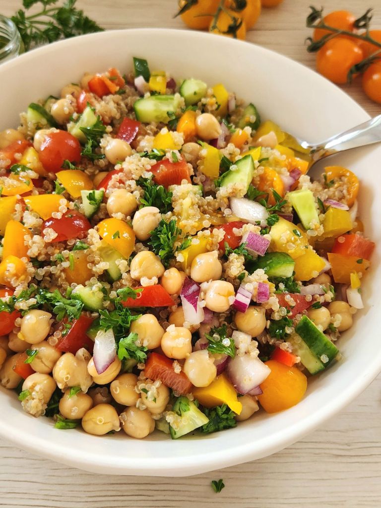 Healthy quinoa chickpea salad with fresh vegetables and lemon herb dressing in a white bowl