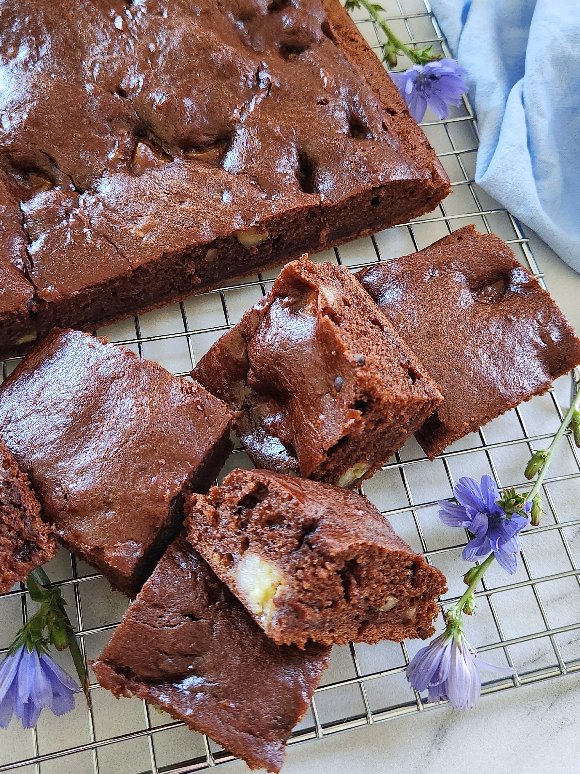 chocolate banana cake cut into squares on a cooling rack, showing a moist, fudgy texture with banana pieces