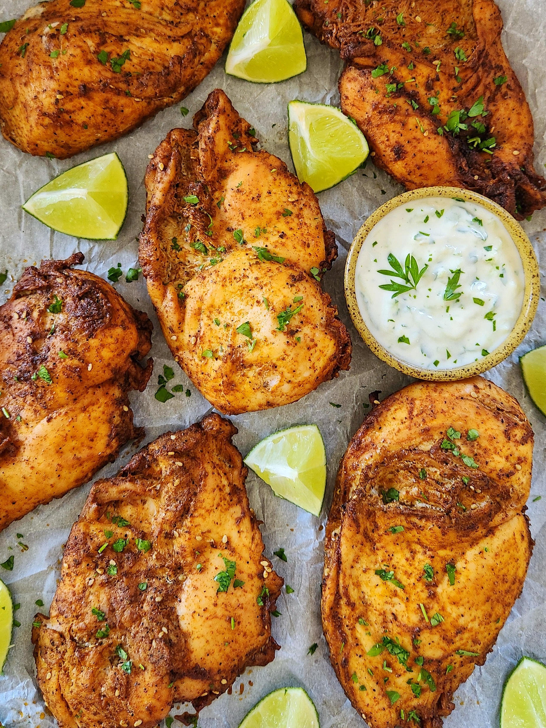 Juicy oven baked chicken breast for tacos with creamy yogurt sauce and fresh lime wedges.