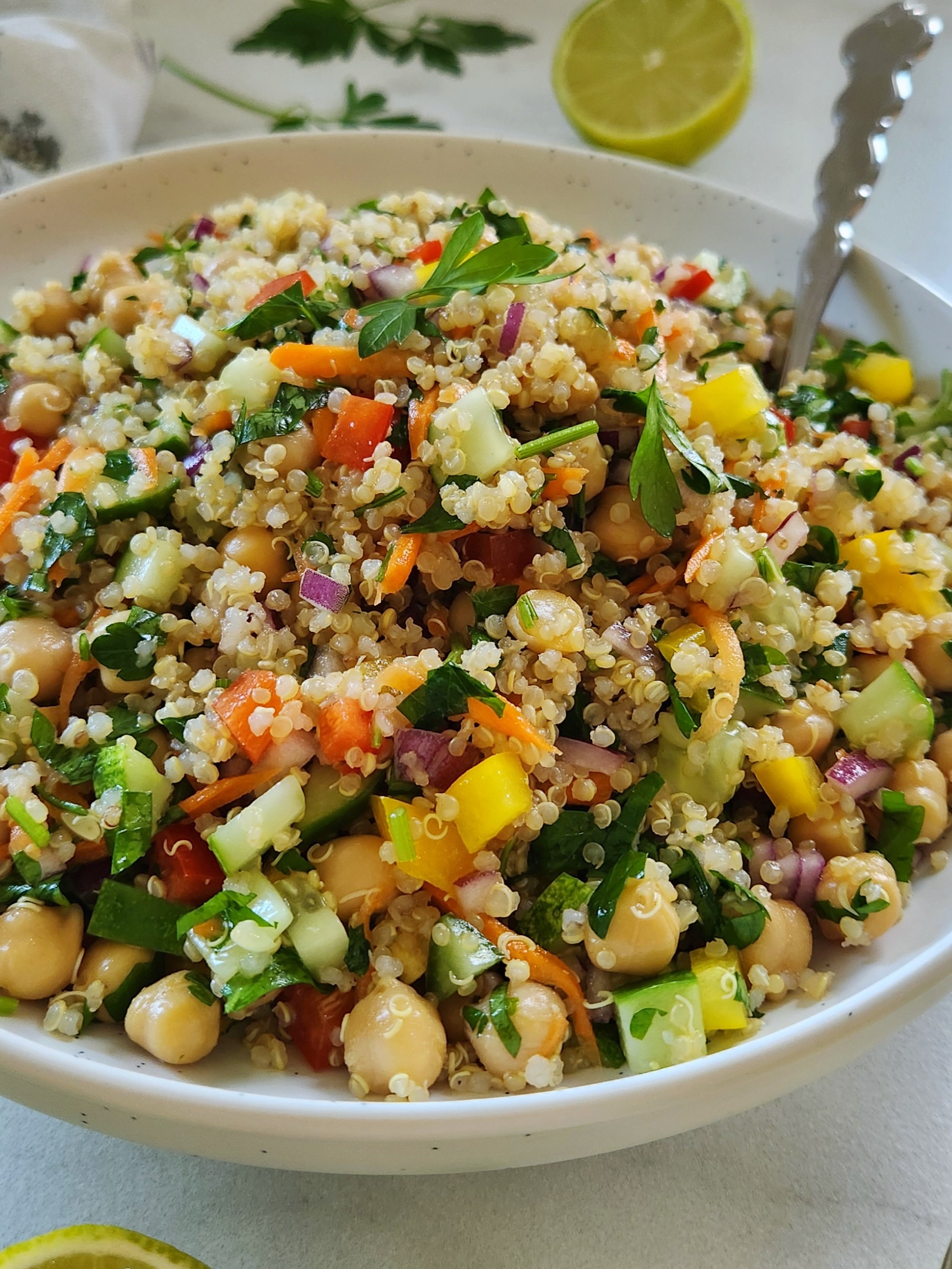 Healthy quinoa chickpea salad with diced cucumber and fresh parsley in a white bowl